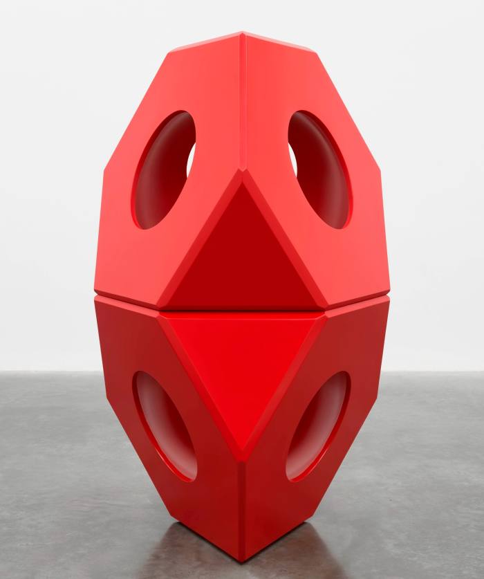 A large red sculpture made up of two stacked geometric shapes with holes running through them 