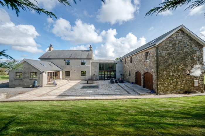 A large u-shaped modern house built in a traditional grey stone style