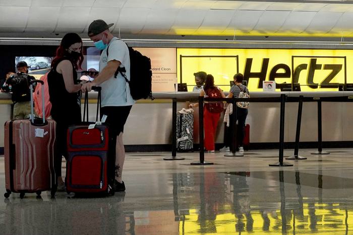 People rent cars at a Hertz car rental counter in the Miami International Airport on October 25, 2021