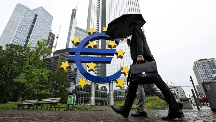 A man walks past the euro symbol former European Central Bank