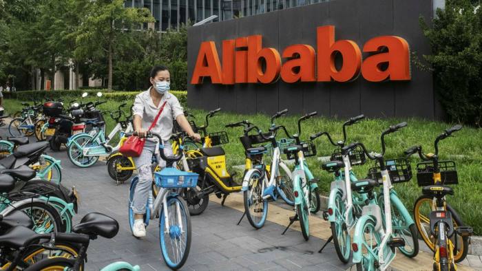 A cyclist rides past the Alibaba Group logo in Beijing