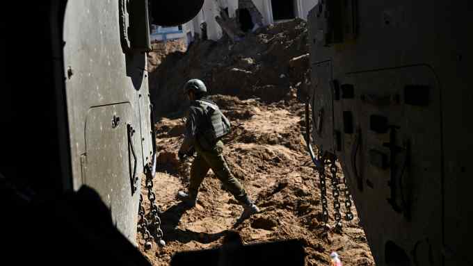 An Israeli soldier walks among destroyed buildings in Gaza
