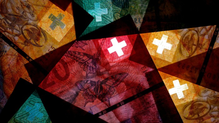 The white cross of the Swiss national flag sits on 50, 20 and 10 Swiss franc banknotes against a black background
