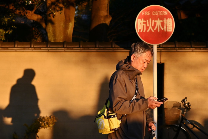 A man looks at his phone next to a fire cistern sign