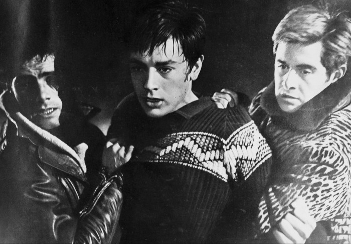 Alain Delon flanked by two men who are cluthing him in ‘Rocco and his Brothers’