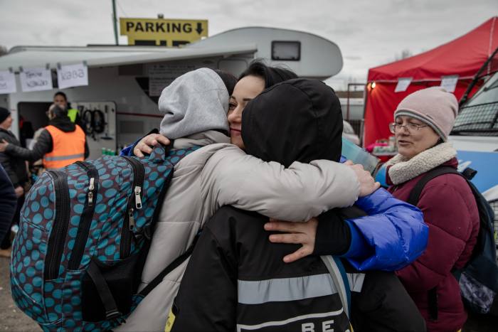 A woman gives a hug to two people in Dolhobyczow, Poland, on 5 March