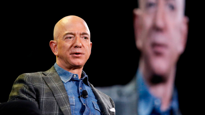 Jeff Bezos in the foreground, with an image of him projected on a screen in the background