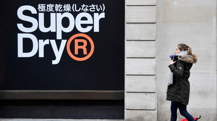 A woman walks past a window display at a Superdry store in London