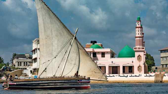 A lateen-rigged dhow boat in front of the Riyadha Mosque