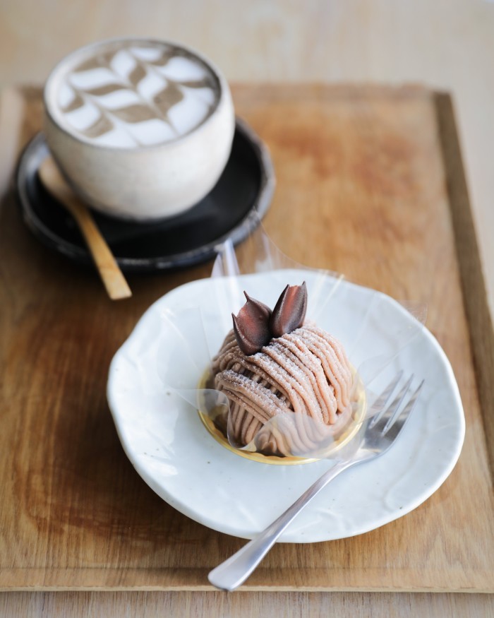 A Mont Blanc bun at WA on a plate, alongside a cup of coffee