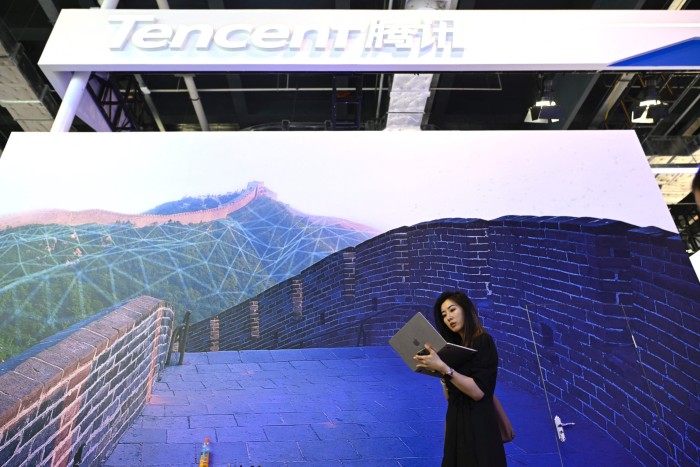 A woman looks at her laptop in front of Tencent’s booth during the World Artificial Intelligence Conference
