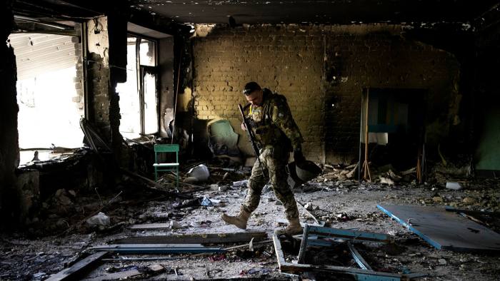 A Ukrainian soldier stands in a bomb-damaged school near Kharkiv