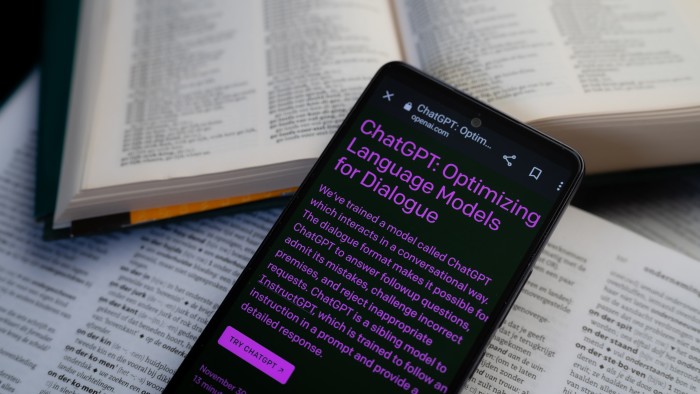 A smart phone on top of two open dictionaries displays the OpenAI page 