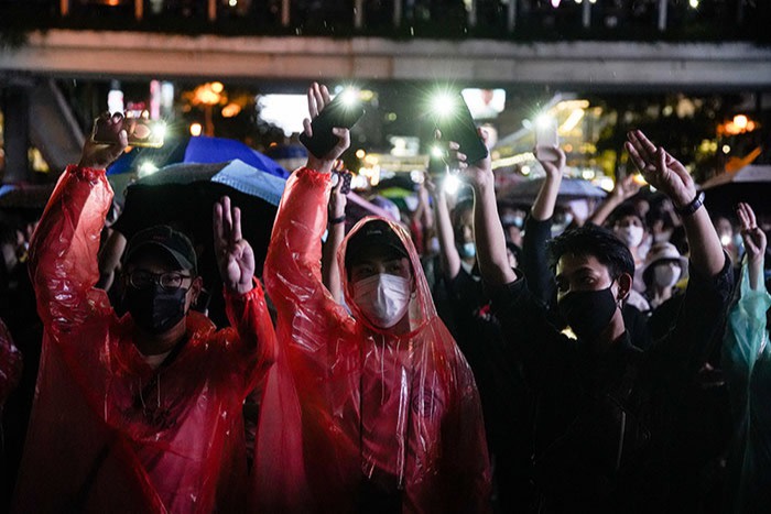 Protesters at a flash demonstration after last month’s emergency decree use umbrellas to shield themselves from water cannons fired by the police