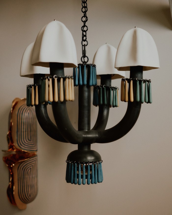Mason-stained stoneware chandelier with slip-cast porcelain shades. Behind is a wall sconce