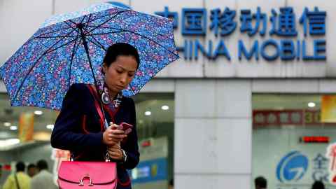 A woman uses her mobile phone in front of a China Mobile office in Shanghai