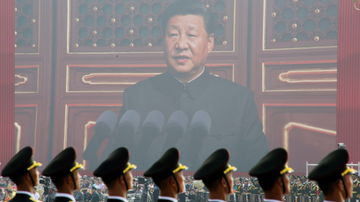 Soldiers of People’s Liberation Army stand before a giant screen as Chinese President Xi Jinping in 2019