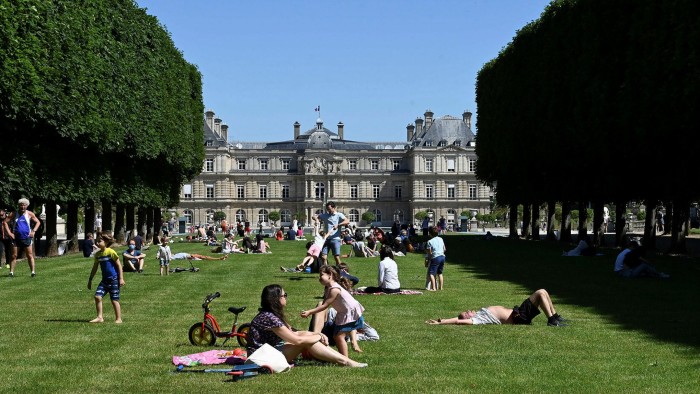 Parisians lie and sit under the sun on the lawns of Jardin du Luxembourg