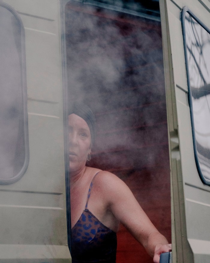 A woman in swimwear looking out through the back door from the Butcher’s Heat sauna van