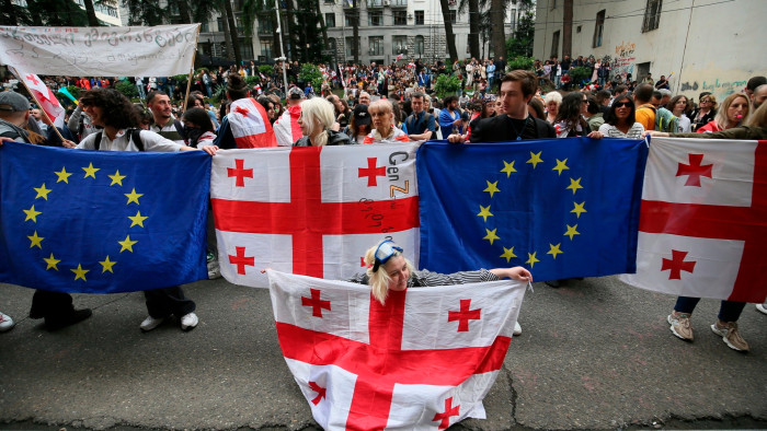 Demonstrators with Georgian national and EU flags gather in front of police during an opposition protest against the foreign influence bill at the Parliamentary building in Tbilisi,