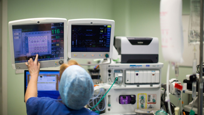 An anesthetist checks information displayed on electronic screens during an operation inside theater at Queen Elizabeth Hospital Birmingham