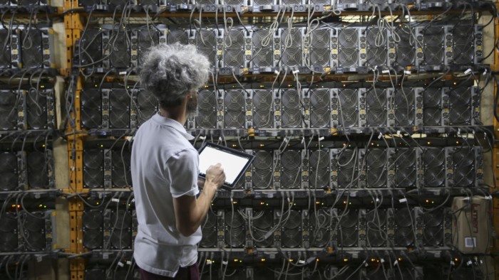 A worker inspects Bitcoin mining machines at a Canada Computational Unlimited computation center