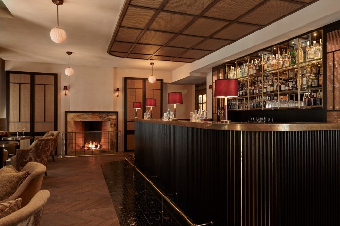 The brass bar at Tata, with globe pendant lighting and a fire lit in the hearth