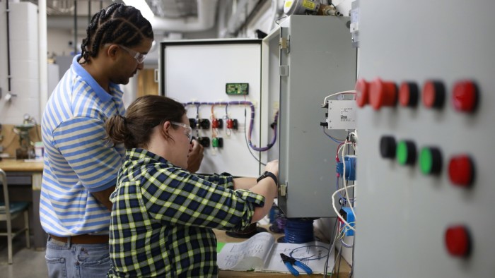 Electrician apprentices, a man and a woman, practice working on a programmable logic controller at the Kentuckiana Electrical Apprenticeship and Training trade school in Louisville, Kentucky, 