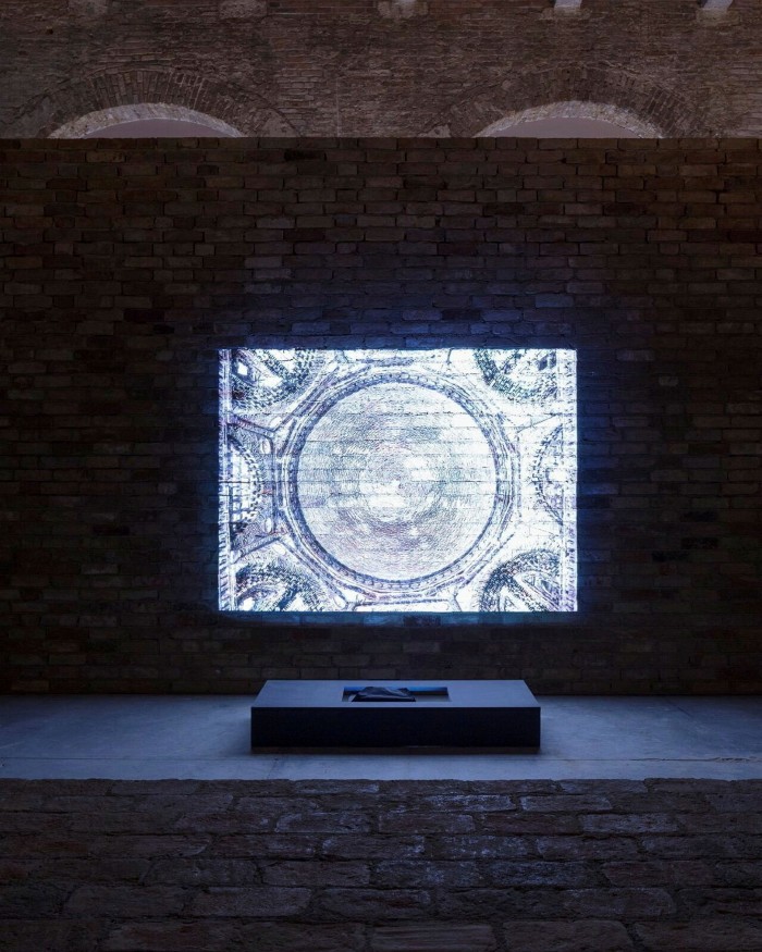 A bright image of architectural detail is projected onto a brick wall