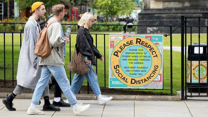 People walk past a sign at St Andrews Square in Edinburgh reminding the public of social-distancing rules