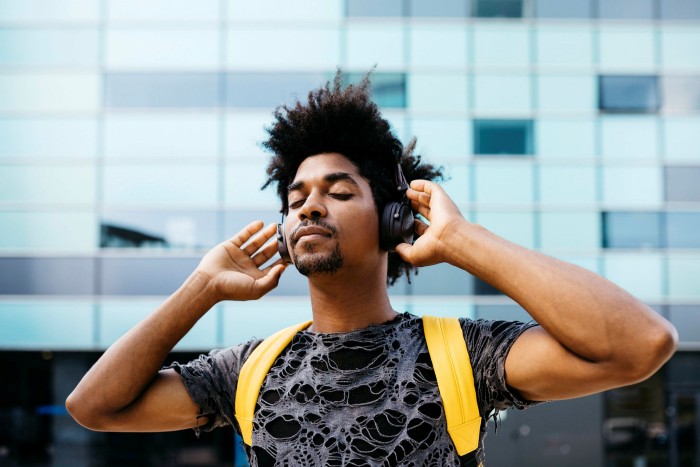 Portrait of man listening music with cordless headphones