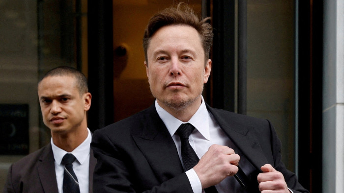 Elon Musk, centre, walks outside with his security detail in Washington