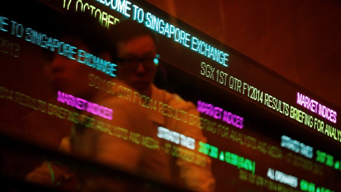 People pass stock index tickers at the Singapore Exchange