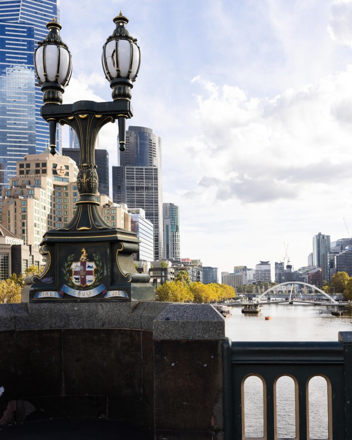 Victorian-style wrought-iron lamps on a plinth on Princes Bridge, with the Yarra in the background