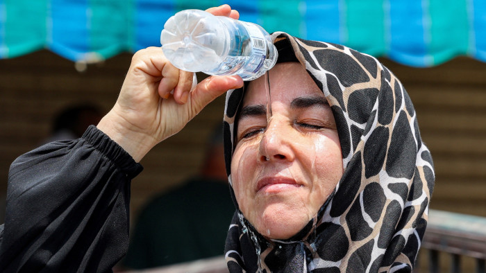 A pilgrim pours cold water on her head to cool off as she waits in Saudi Arabia’s holy city of Mecca