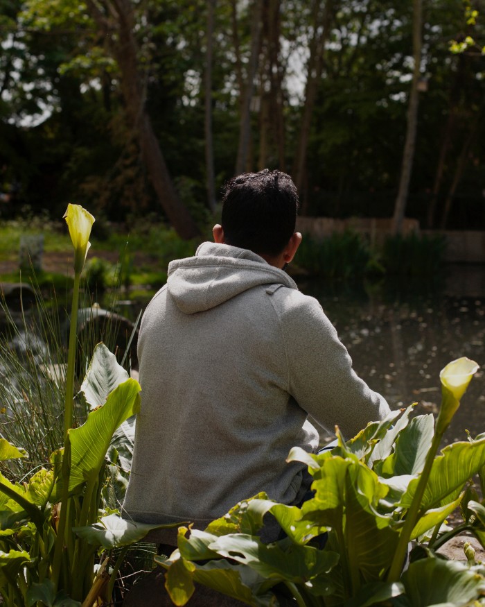 Tamim Hasan sits by a pond at a park in east London and looks out on the water