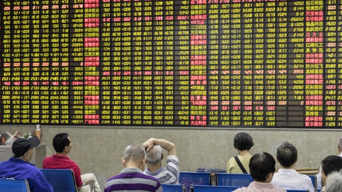 Investors sit in front of an electronic stock board at a securities brokerage in Shanghai, China