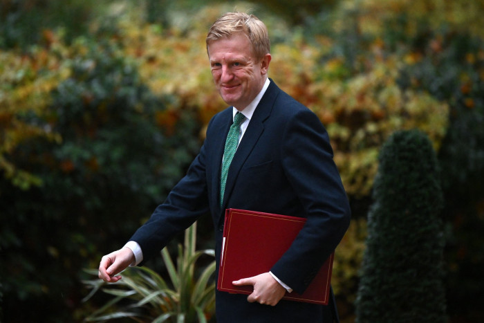 Oliver Dowden carries a folder of briefing papers