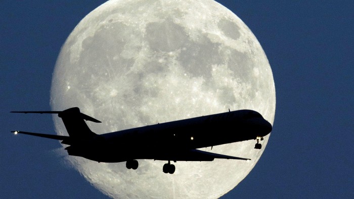 A plane in the air with the moon in the background