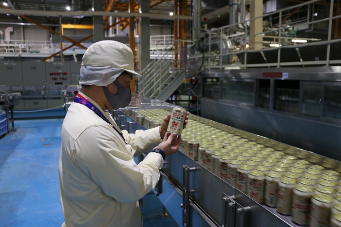 A worker inspects a drinks can in a Kirin factory