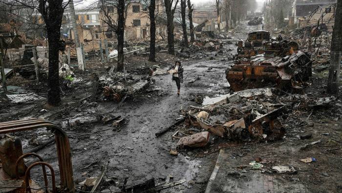 A woman walks past destroyed Russian tanks in Bucha 