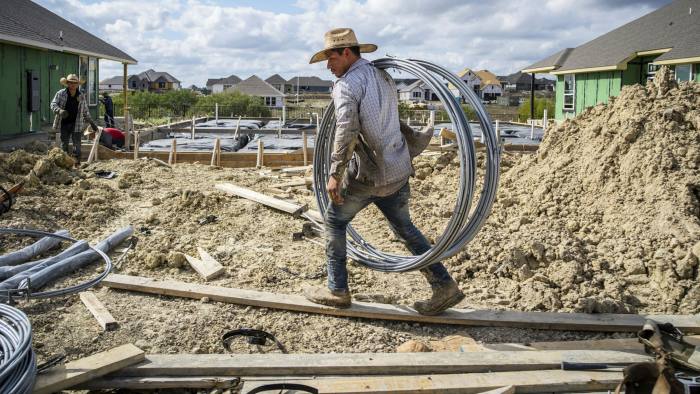 A construction worker carries materials while building a new home in the Sunfield neighborhood of Buda, Texas