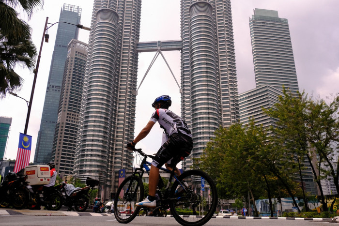 A cyclist cycles past the Petronas Towers in Kuala Lumpur, Malaysia