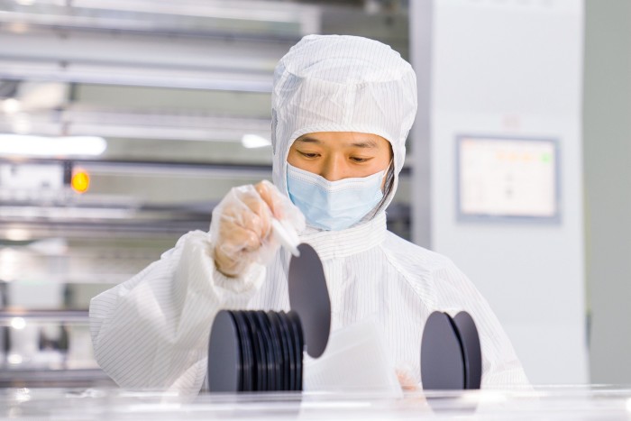 A worker in a lab coat makes and tests semiconductor power device chip