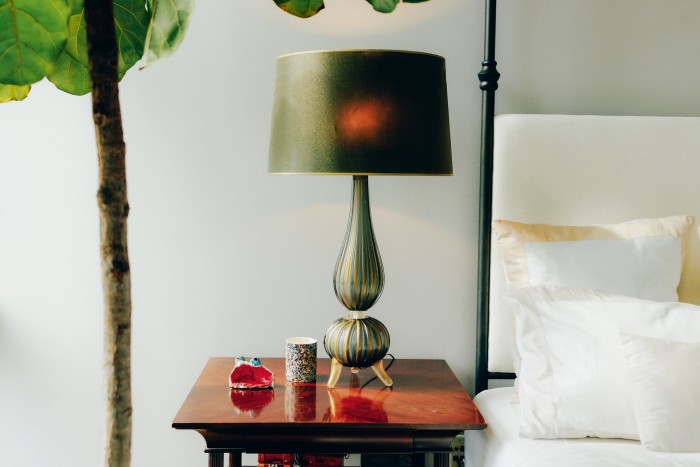 Her bedside table, with one of a pair of vintage Murano lamps found at a Paris flea market, plus her son’s art piece