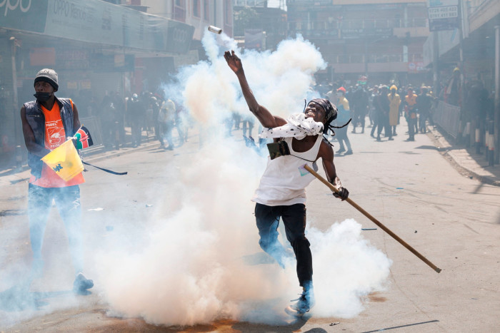 A protester lobs back a tear gas canister at police