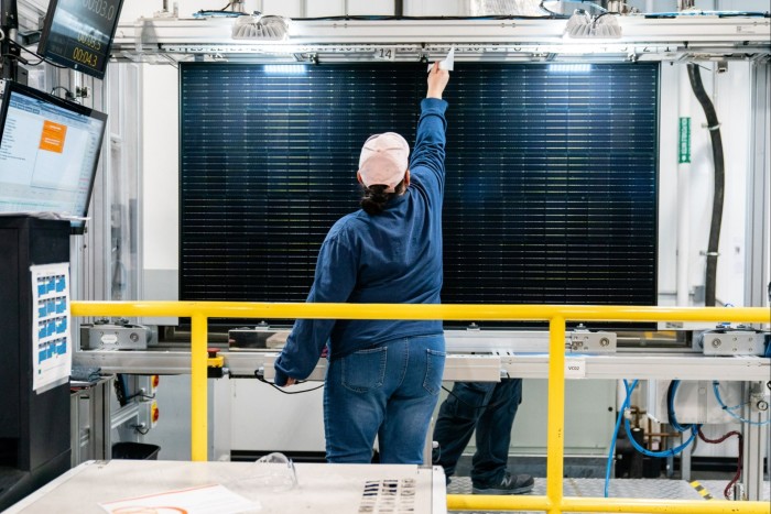 A quality control worker checks a solar panel at the Hanwha Q Cells solar cell and module manufacturing facility in Dalton, Georgia, US