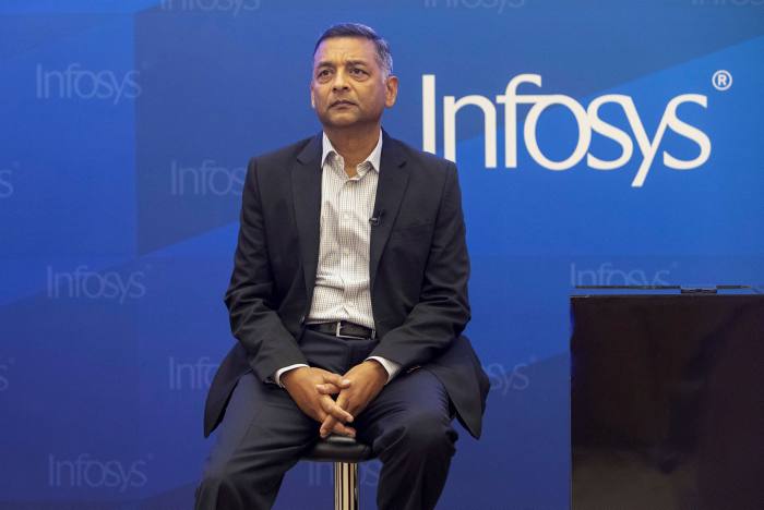 Nilanjan Roy, chief financial officer of Infosys. A man onstage sitting on a barstool. Behind him is the Infosys name brand.