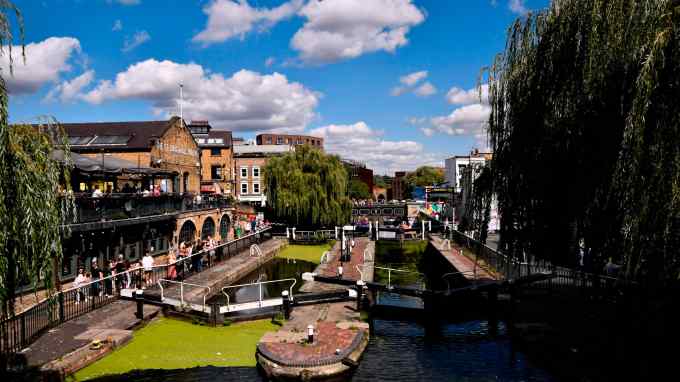People walk around the Camden Lock and canal on a sunny day