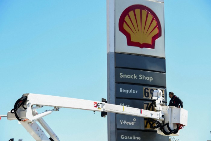 An electrical contractor uses a hydraulic platform to reach a price display at a Los Angeles petrol station